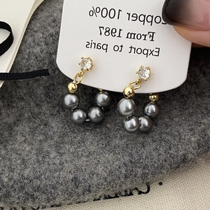 Macro detail of gold-plated earrings with grey pearls and sparkling zircon accents