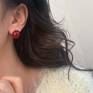 Close-up of elegant cherry red spherical stud earrings worn on model for a chic look