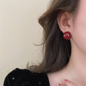 Close-up of a model wearing smooth red enamel ball earrings with a vintage style
