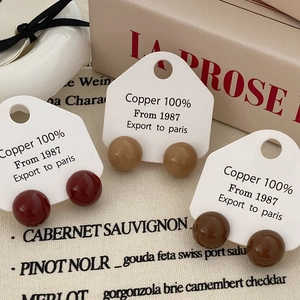 Detail of red and brown spherical resin stud earrings on vintage fabric background