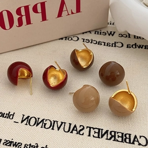 Detailed view of spherical red enamel hoop earrings on minimalist canvas texture