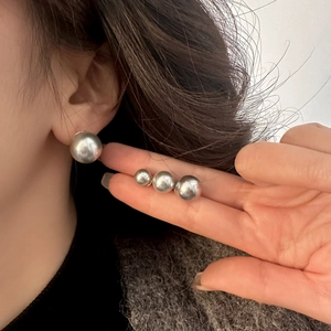 Elegant round silver pearl stud earrings shown in three sizes on a model for scale