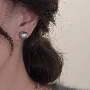Close-up of elegant grey round pearl stud earring worn on model for a french style look