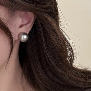 Close-up of large 12mm grey pearl stud earring with metallic luster on model's ear