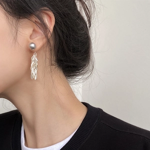 Close-up of elegant silver leaf tassel earrings worn by a model with a minimalist design