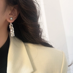 Close-up of model wearing silver leaf tassel earrings with a grey pearl stud