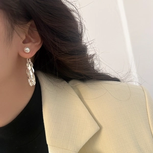 Close-up of pearl leaf tassel earrings in silver finish on a model's ear