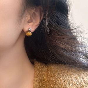 Elegant tiger eye stone stud earrings with zircon inlay worn on a model's ear