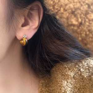 Detail of natural tiger eye stone stud earring with zircon on model's ear