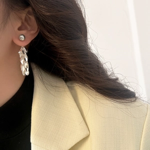Detail of silver leaf tassel earrings with metallic bead and shiny chain on a model