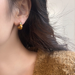 Macro detail of tiger eye stone stud earrings with zircon accent worn by model
