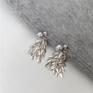 Elegant silver leaf tassel earrings with grey pearls on grey knitted background