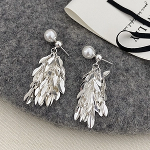 Detailed view of leaf-shaped silver tassels and pearls on textured dark grey fabric