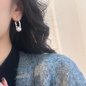 Gros plan détaillé d'une boucle d'oreille en argent avec perle blanche de forme en U