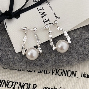 Détail macro de boucles d'oreilles en U avec perles argentées et grandes perles blanches