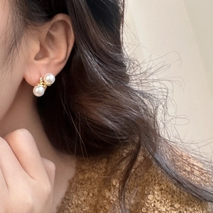 Detail of elegant double pearl gold twist earrings worn for a French vintage aesthetic