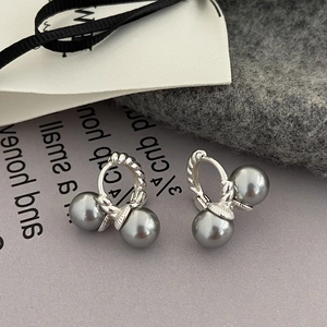 Twisted silver metal hoop earrings with grey pearls on minimalist neutral background