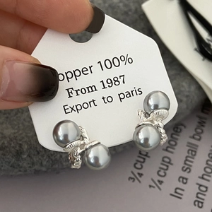Detail of twisted silver earrings with grey double pearls and copper shell texture