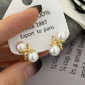 Detail of twisted gold earrings featuring elegant double white pearls on display