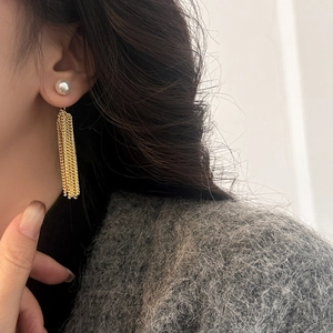 Elegant gray pearl stud earrings with long gold tassel chains shown on a model