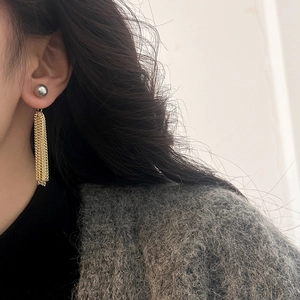 Detail view of long tassel earrings with grey pearls and fine golden chains on a model