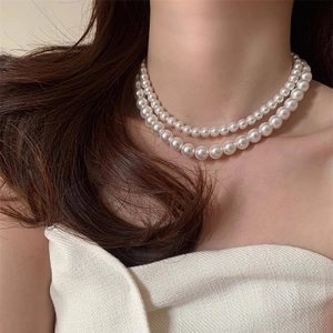 Gros plan d'un collier de perles blanches double épaisseur porté par un mannequin