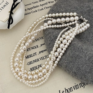 Détail d'un collier de perles multicouche avec fermoir argenté sur fond texturé