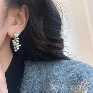 Close-up of pearl drop earrings with polished silver metal spheres in a grape cluster style
