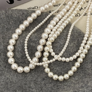 Vue détaillée de colliers de perles blanches superposés de différentes tailles et éclats