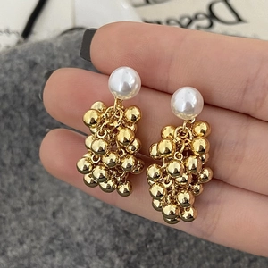Detailed macro view of French vintage earrings featuring white pearls and gold metal spheres