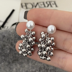 Detail of hand-held French vintage pearl earrings with silver metal bead tassels