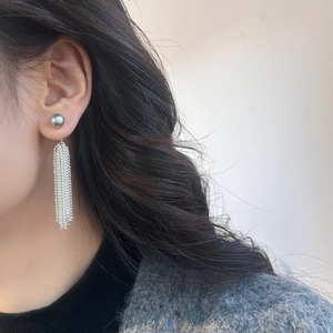 Detail of elegant silver waterfall tassel earrings with grey pearl on model