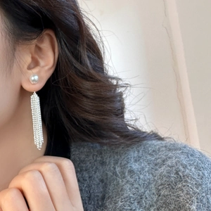 Detail shot of pearl tassel earrings featuring cascading silver chains and elegant white pearls