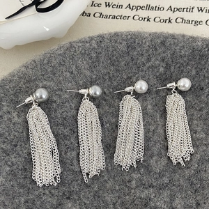 Detailed close-up of grey and white pearl tassel earrings on a textured wool background