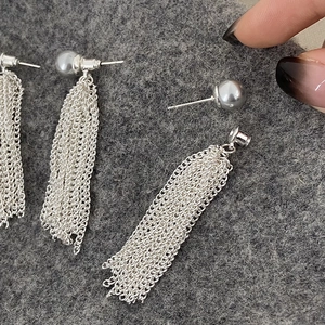 Detail of detachable grey pearl earrings with long silver cascading tassel chains