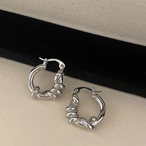Dettaglio macro di orecchini a cerchio intrecciati argento con design a spirale
