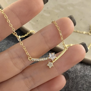 Macro detail of gold star zircon necklace featuring a double-star pendant on a fine chain