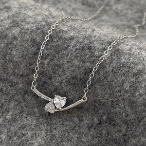 Macro shot of silver star heart zircon necklace pendant on grey textured knit fabric