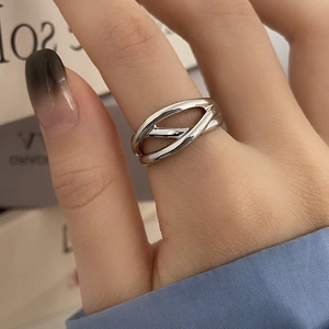 Macro detail of silver crossover ring featuring a hollow twisted geometric design