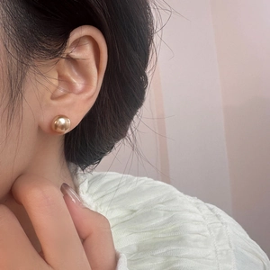 Nahaufnahme eines minimalistischen goldenen Kugelohrrings am Model für einen edlen Look