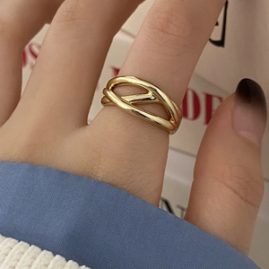 Detail of minimalist gold-plated crossover ring with multi-layer hollow knotted design