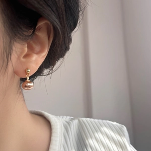 Detail eines eleganten Gold-Ohrsteckers mit großer ovaler rosa Perle am Model getragen