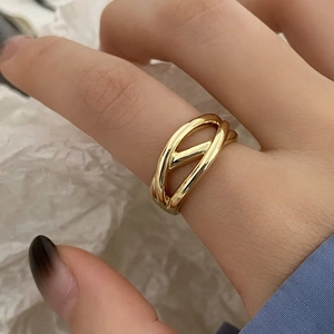 Close-up of minimalist gold-finish crisscross hollow geometric ring worn on finger