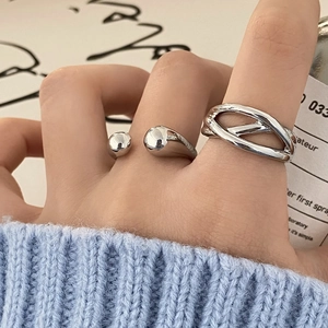 Macro detail of silver crossover rings with minimalist twist and spherical open design