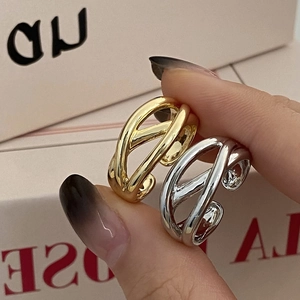 Close-up of modern minimalist gold and silver intertwined X-shaped crossover open rings