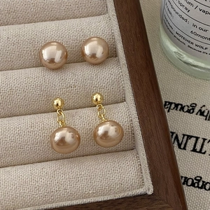 Elegantes Set aus champagnerfarbenen Perlenohrringen mit Steckern auf Holztablett