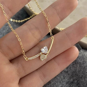 Detailed shot of gold-plated necklace featuring double heart pendants with clear zircons