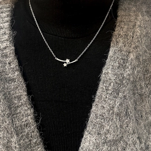 Star and heart zircon necklace in silver finish worn on a grey knit sweater