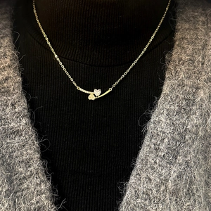 Elegant gold heart and star zircon necklace worn on a black sweater for a layered look
