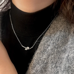 Macro shot of silver dual-heart pendant with pave zircons on thin chain for women